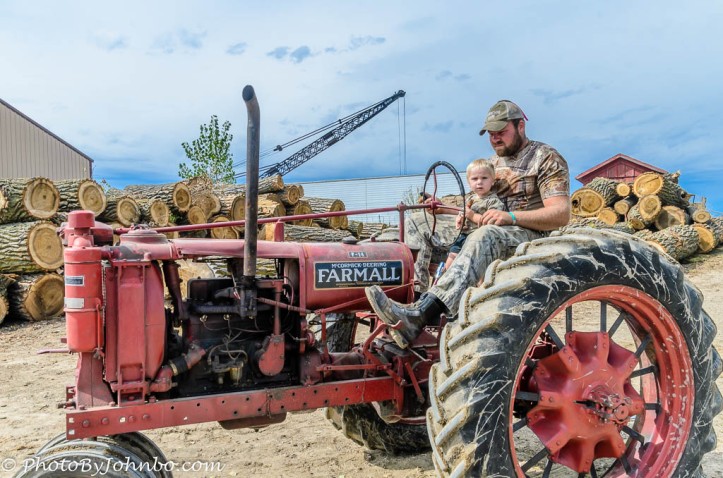 A boy and his dad spend quality time on the old Farmall.